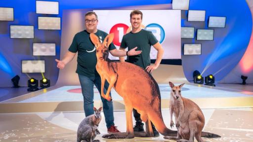 1, 2 oder 3: Moderator Elton steht mit Studiogast Daniel Materna vor der Vidiwall im "1, 2 oder 3"-Studio. Vor ihnen sind drei Känguru-Aufsteller platziert.