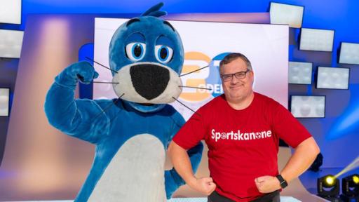 1, 2 oder 3: Moderator Elton und Piet Flosse stehen vor der Vidiwall im "1, 2 oder 3"-Studio. Elton trägt ein Tshirt auf dem "Sportskanone" steht.