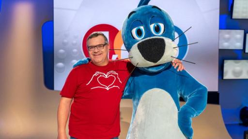1, 2 oder 3: Moderator Elton und Piet Flosse stehen Arm in Arm vor der Vidiwall im "1, 2 oder 3"-Studio. Elton trägt ein Tshirt auf dem ein Herz abgebildet ist.