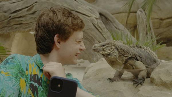 Aaron (Philip Müller) mach sein Selfie mit dem Mini-Dino. | Rechte: KiKA/2021 eitelsonnenschein