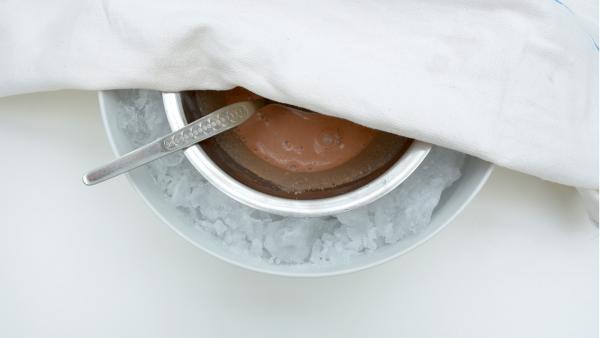 Lege ein Küchenhandtuch über die Schüssel. Dadurch verhinderst du, dass Wärme von außen in die Schüssel gelangt.<br/><br/>Stelle dann die Schüssel eine Stunde lang in einen kühlen Raum. Rühre alle fünf Minuten, die Kakaomischung um. Passe auf, dass kein salziges Eiswasser in die Mischung schwappt.<br/> | Rechte: KiKA