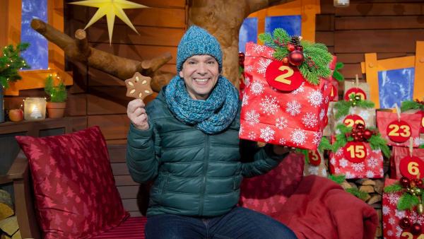 Juri hat ein Päckchen mit der Nummer zwei und einen sternenförmigen Lebkuchen in der Hand.