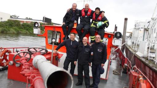 Der Wer-passt-auf-im-Hafen-Check / Checker Can (oben rechts) auf einem Löschboot bei der Hafenfeuerwehr in Hamburg.