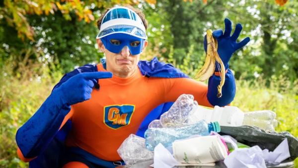 Werde zum Müll-Superheld | Julian im Superhelden-Kostüm vor einem vollgepackten Mülleimer. | Bild: BR/megaherz gmbh | Rechte: BR/megaherz gmbh