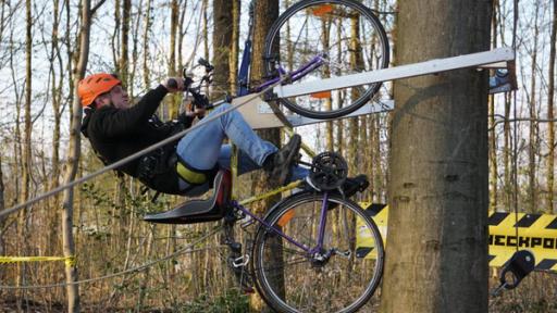 Checkpoint: Testteamer Cem fährt mit dem fahrrad einen Baumstamm hoch