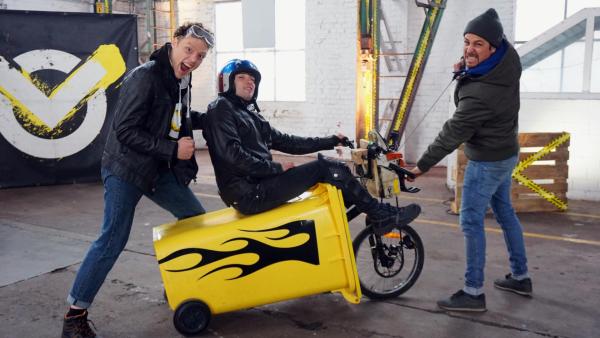 Checkpoint: Tommy Scheel zieht das Checkpoint Team auf einer gelben Mülltonne mit Rädern. | Rechte: ZDF
