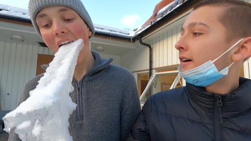 Max ist lins zu sehen, Hinnerk rechts. Max beißt in einen großen Eiszapfen, Hinnerk schaut ihm zu.