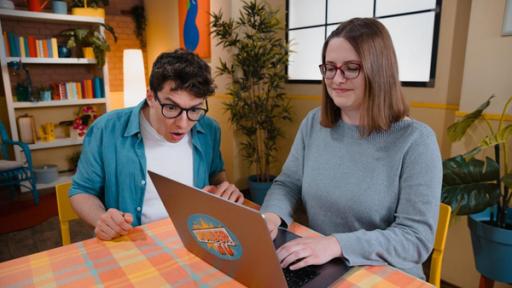 "Das Wunder DU - Voll auf Geschwindigkeit": Christoph (l.) sitzt neben Miriam (r.) am Tisch und schaut erstaunt, wie Miriam auf einem Laptop schreibt.