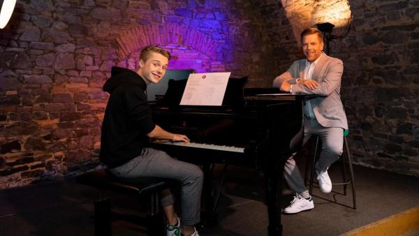 "Dein Song - Tipps von den Paten - Folge 13":  Lion sitzt am Flügel im Jazzkeller. Ihm gegenüber sitzt sein Pate Tom Gaebel mit den Armen auf dem Flügel abgelegt und lächelt in die Kamera. | Rechte: ZDF