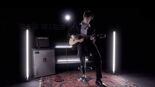 Moritz trägt einen schwarzen Anzug, sitzt in einem dunklen Raum und spielt Gitarre. | Rechte: BSB Film; ZDF