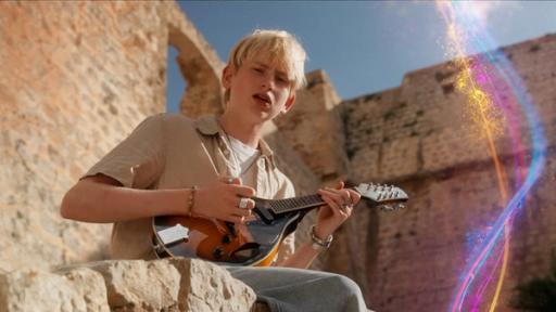 Theodor sitzt auf einer Steinmauer und spielt auf einer Ukulele seinen Song