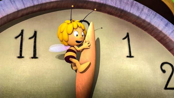 Maja hängt am Minutenzeiger einer riesigen Uhr. Der Minutenzeiger steht auf kurz nach Zwölf. | Rechte: Nach Waldemar Bonsels “Die Biene Maja”. © 2012 Studio 100 Animation 