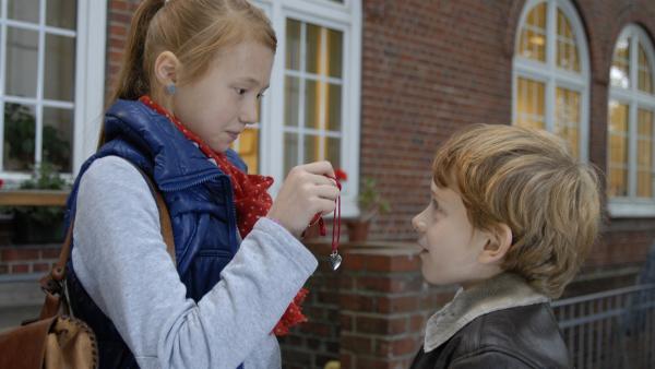 Emma (Aurelia Stern) zeigt Henri (Sammy O'Leary) ein Geschenk von ihremheimlichen Verehrer. | Rechte: NDR/Romano Ruhnau
