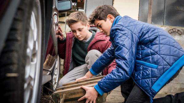 Moritz und Hakim von "Die Pfefferkörner" untersuchen einen Autoreifen.