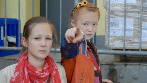 Lina (Lale H. Mann) steht neben Emma (Aurelia Stern), die mit dem Finger auf etwas zeigt.