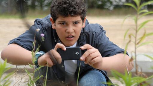 Anton (Danilo Kamber) hält ein Smartphone in der Hand.