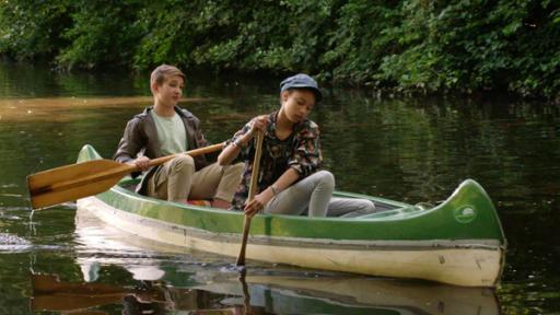 Lisha und Johannes sitzen in einem Boot auf dem Wasser.