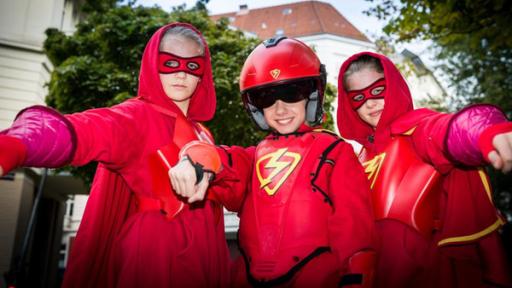 Stella (Zoë Malia Moon, links), der Rote Blitz (Lilly Barshy, Mitte) und Pinja (Sina Michel) in roten Superhelden-Kostümen.