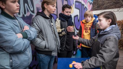 Yanis (Tom Philipp, rechts) kassiert beim Hütchenspiel ab