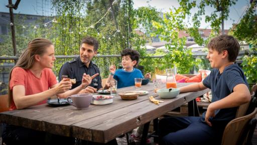 Freya, Nazim mit Milan und Rafa sitzen zusammen am Frühstückstisch 