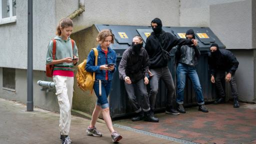 Lou und Tali auf dem Weg zur Schule, bei Mülltonnen lauert eine Gang.