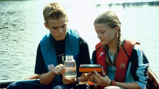 Fiete und Natascha nehmen eine Wasserprobe in der Elbe.