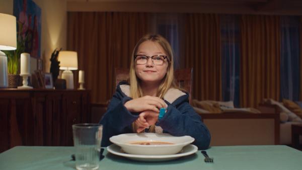Floor sitzt beim Abendessen und spielt mit ihrer neuen Armbanduhr. | Rechte: NL Film