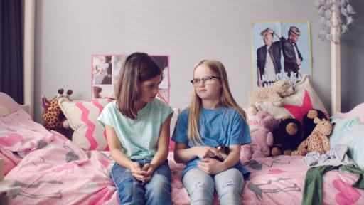 Floor (Bobbie Mulder) (r.) sitzt mit Margreet (l.) auf dem Bett und hat das neue Meerschweinchen auf dem Schoß