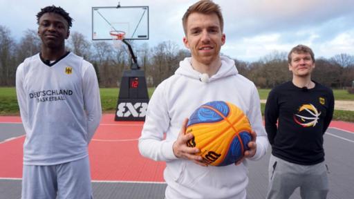 Die Sportmacher: Stefan (links) und Laura (rechts) stehen nebeneinander vor dem Sportmacher-Logo. Stefan hält einen Basketball in den Händen und Laura ein Springseil.