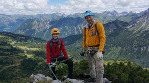 Laura und Bergführer Ecke stehen vor einem beeindruckenden Bergpanorama.