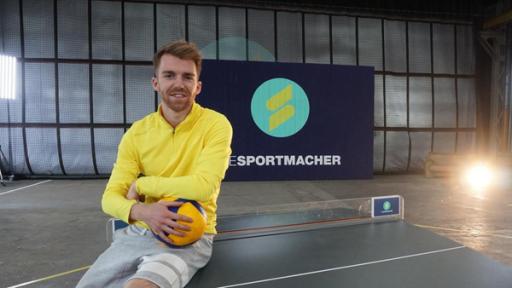 Stefan sitzt mit einem Volleyball auf einer Tischtennisplatte.