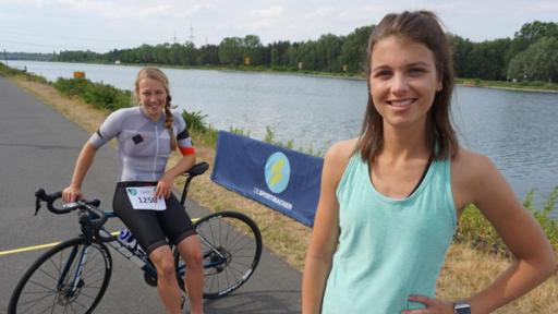 Caro (links) sitzt auf ihrem Rad und hält ihre Startnummer in der Hand. Laura (rechts) steht  im Sportoufit vor ihr.