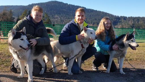 "Die Sportmacher": Moderator Stefan, Rosalie und Louis sitzen neben drei angeleinten Huskys und streicheln sie.