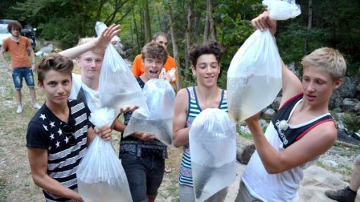 Die Jungs tragen Wasserbeutel mit Fischen darin