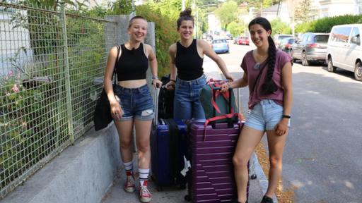 Greta, Karima und Sienna stehen mit ihen Koffern auf dem Gehweg