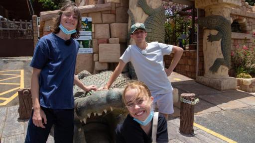 Leo, Lia und Adis stehen vor dem Eingang zu einem Tierpark