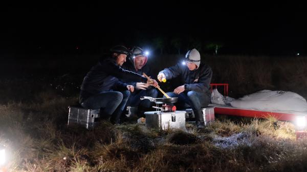 Speisen im Moor. Tommy Scheel, Kenneth und Cem bei der Zubereitung ihres Abendessens unter freiem Himmel. | Rechte: ZDF/Annalena Renneisen