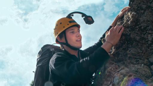 Ben hat einen Helm mit Action-Kamera auf und klettert mit seinem Rucksack eine steile Felswand hoch.