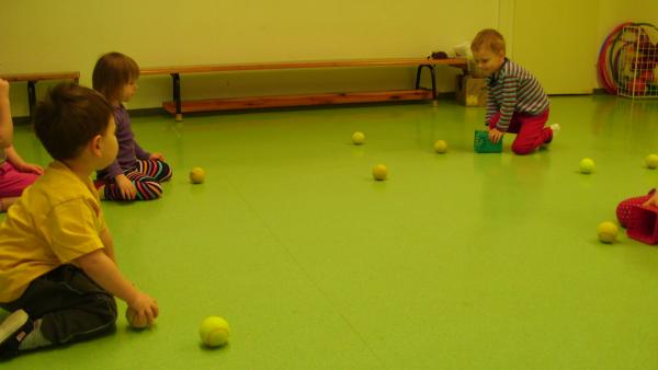 Kinder fangen mit Besteckkörbchen Tennisbälle.