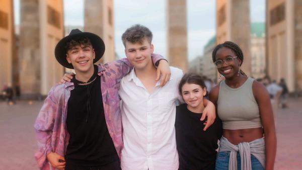 Dasha, Ros, Diana und Anton stehen Arm in Arm vor dem Brandenburger Tor.