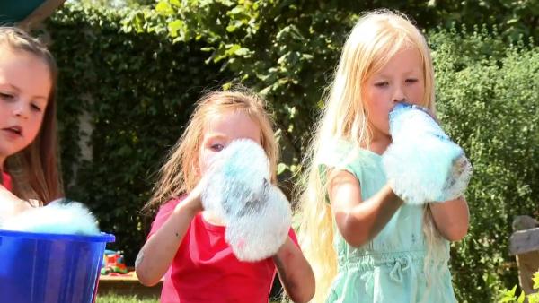 Melina, Karina und Gloria machen Regenbogenschaum mit Plastikflaschen, Lebensmittelfarbe und Seifenlauge. 