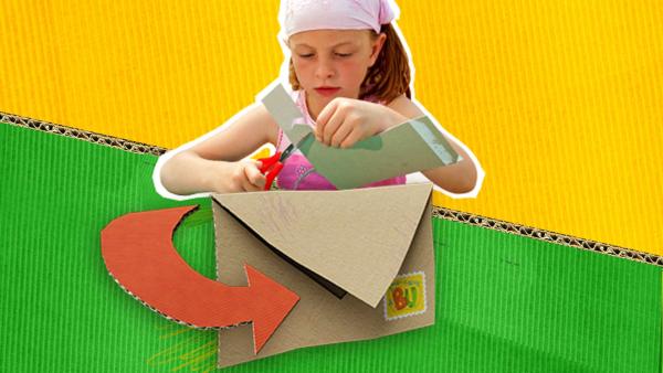 Ein Kind beim Ausschneiden eines Stücks Pappe, im Vordergrund ein Briefumschlag.