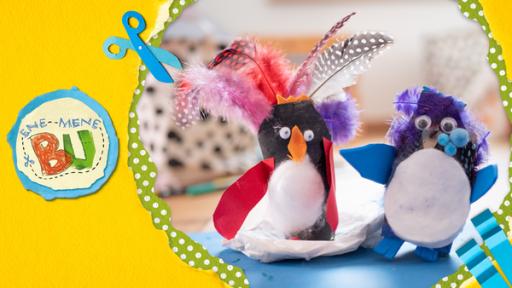 Zwei Pinguine aus Klopapierrollen geschmückt mit Federn, Papier, Watte und Pompons.