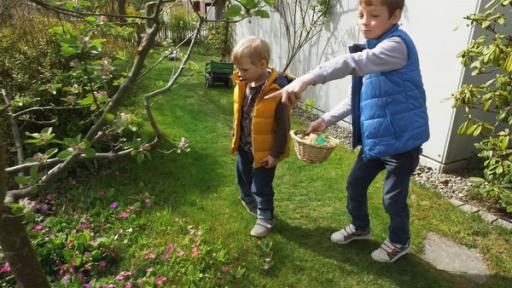 Drei Kinder stehen draußen hinter ihren Osterkörbchen. Darin befinden sich viele Süßigkeiten.