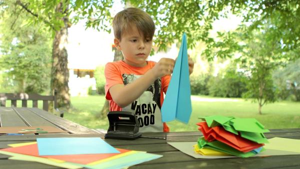 Adnan faltet einen blauen Papierflieger. | Rechte: KiKA/Motion Works GmbH