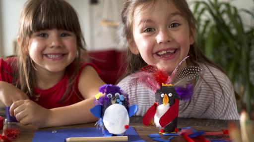 Liselotte und Palina basteln Pinguine aus Toilettenpapierrollen.