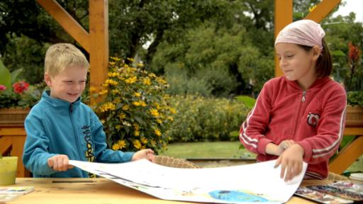 Zwei Kinder stehen draußen an einem Tisch. Vor ihnen liegt ihr selbst gemaltes Bild.