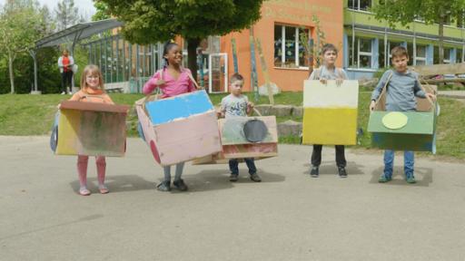 Tom und seine Freunde stehen draußen vor einem Gebäude nebeneinander und zeigen ihre Busse.