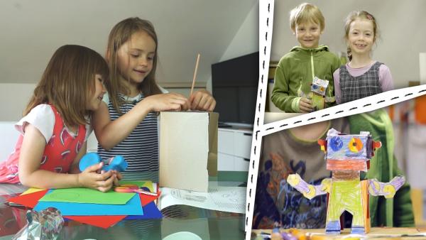 Kinder basteln. Zwei Kinder halten einen Papier-Roboter. Ein bunter, selbstgebastelter Roboter.