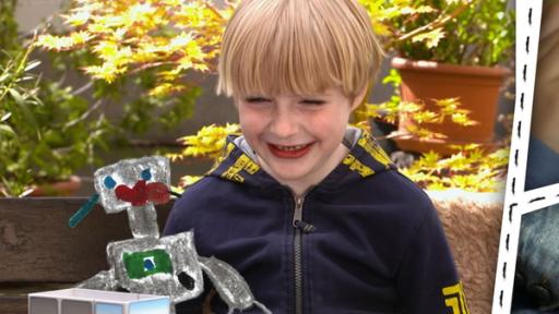 Ein Kind mit Roboter und Farbkasten, Kinderhände mit Lochschablone und einem Vergrößerungsglas.